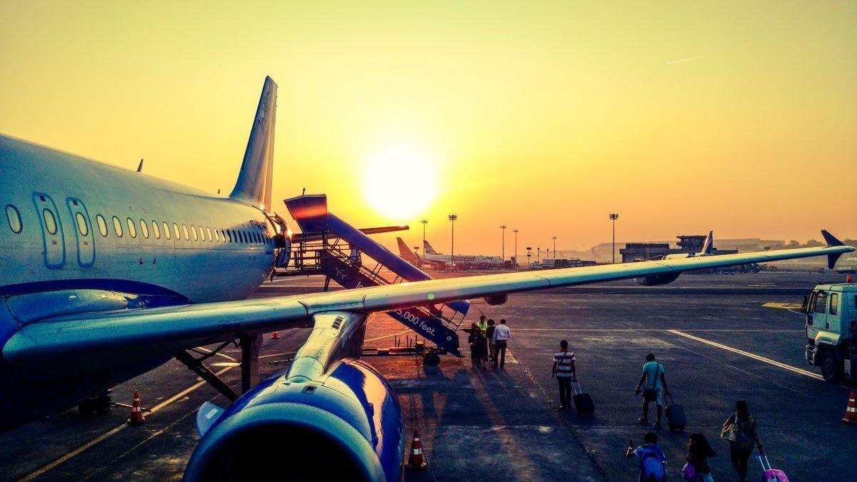 Wide-body aircraft on the apron at sunset with ground crew loading