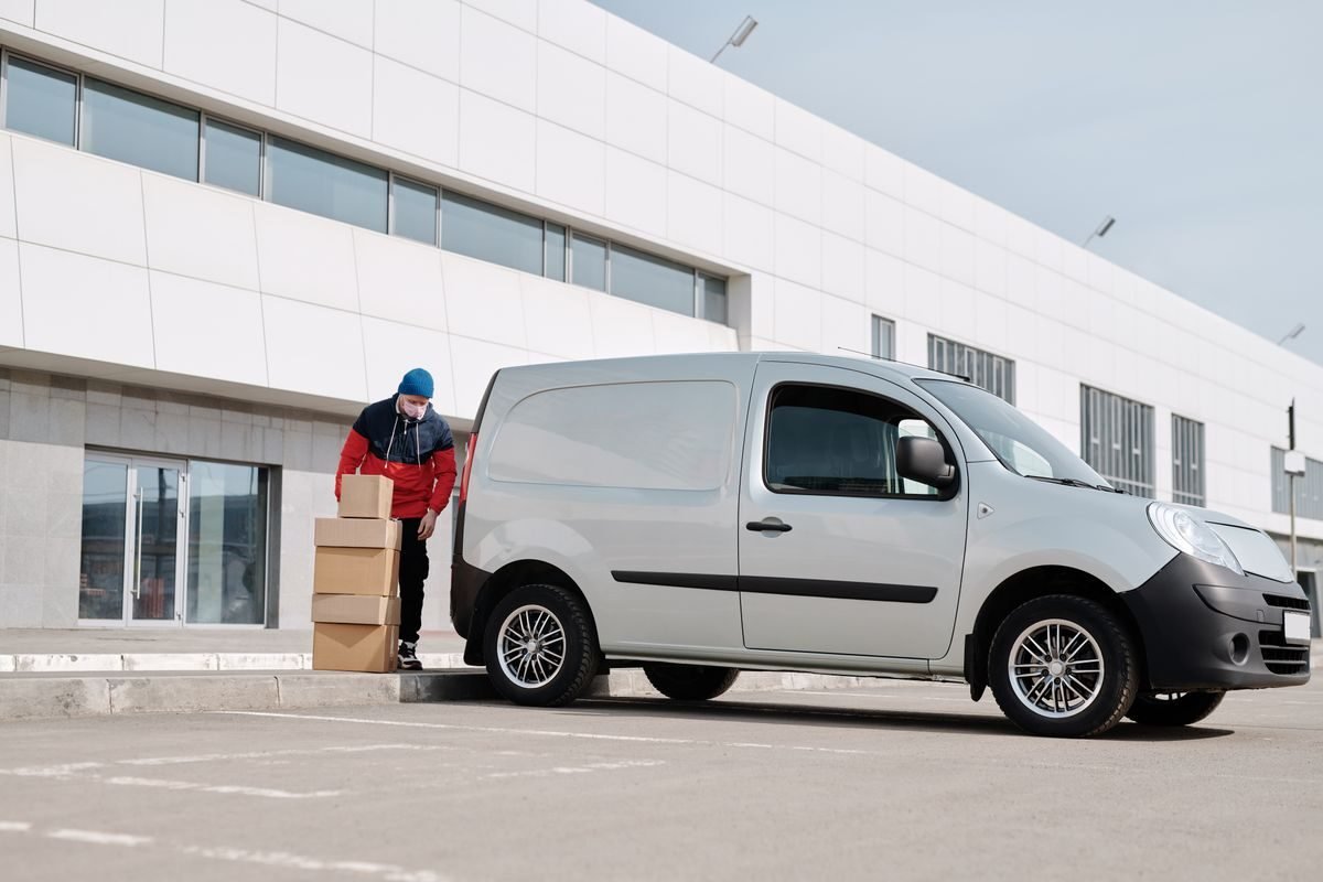 Driver loading cartons into a delivery van outside a warehouse
