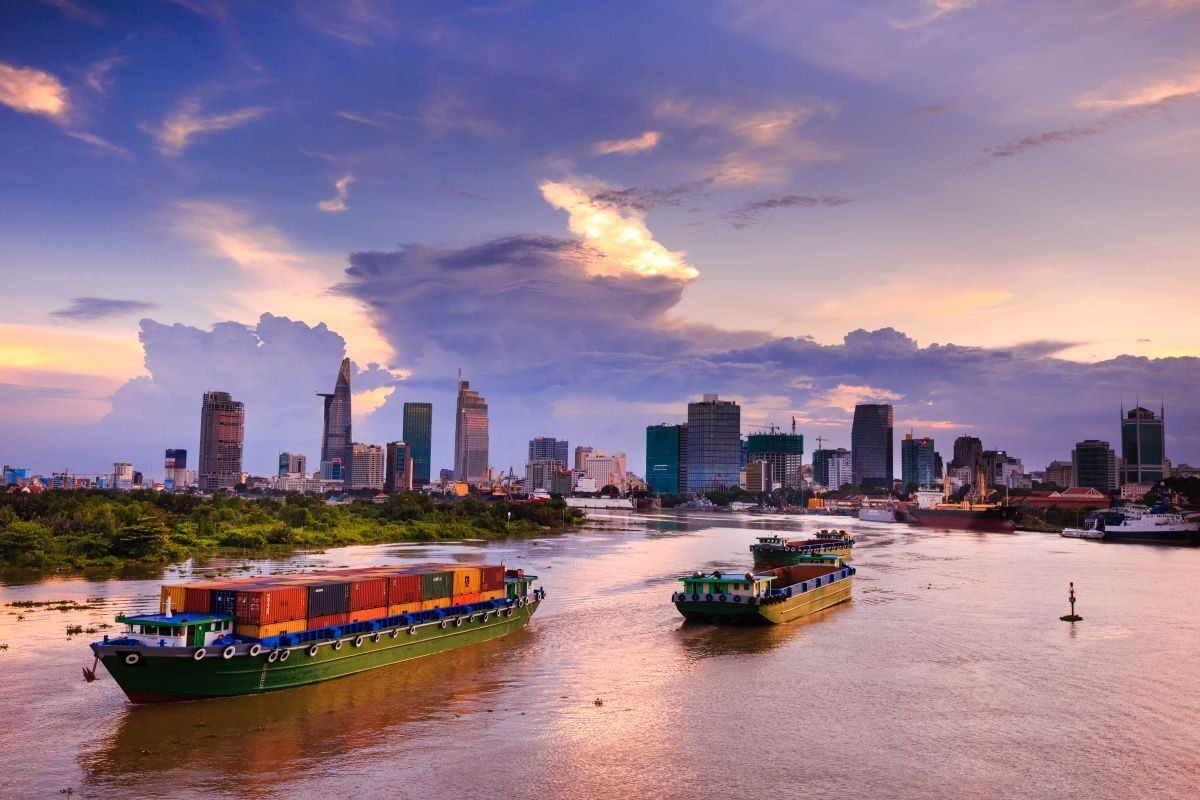 Container vessel on the water at dusk with a city skyline behind